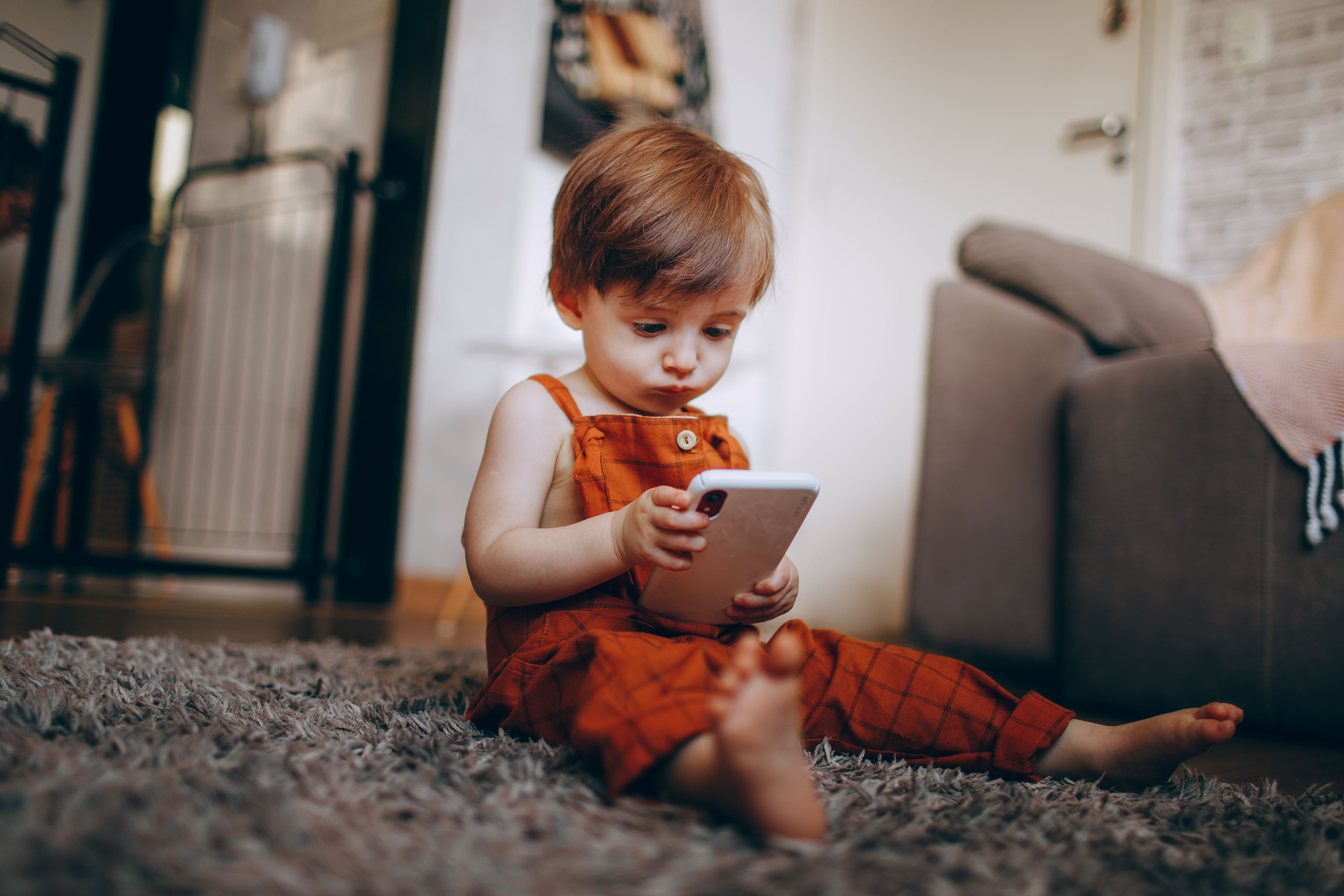 Toddler Engaged with Smartphone Indoors · Free Stock Photo