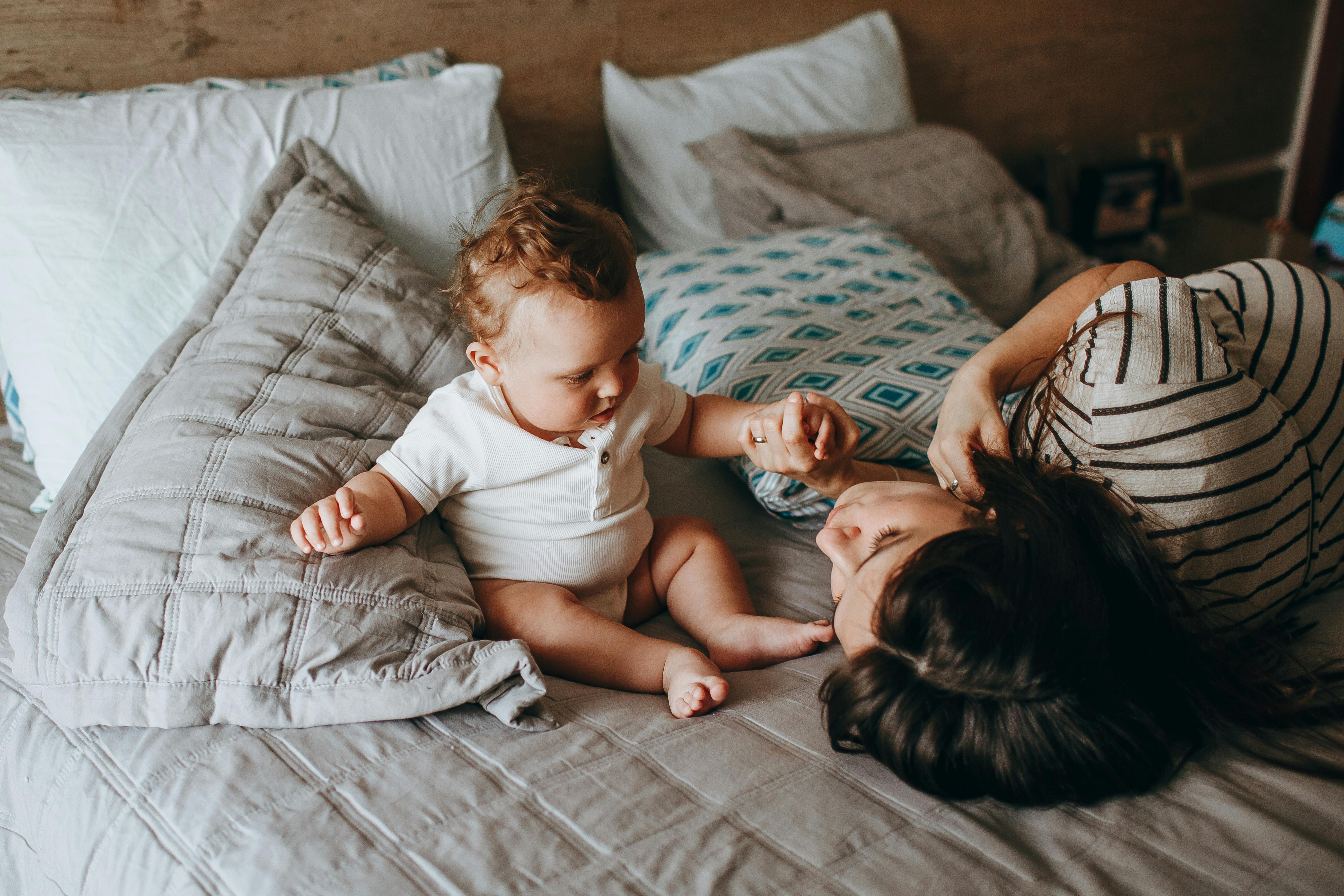 mother lying down with newborn son on bed