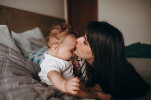 Free A tender moment between mother and baby in a cozy bedroom, conveying love and affection. Stock Photo