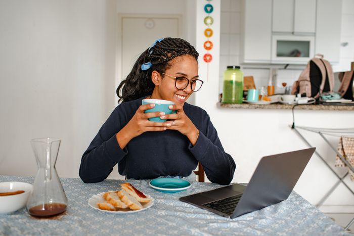 Person with a coffee working at a laptop — photo by Helena Lopes on Pexels