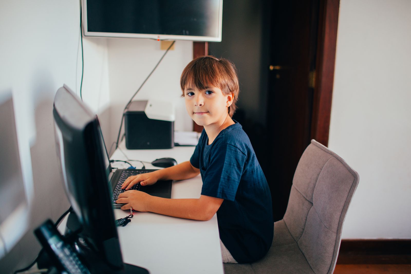 Desktop Computer Boy Using Boy Wearing Blue T Shirt Using Black Laptop Computer in a Dim Lighted ...