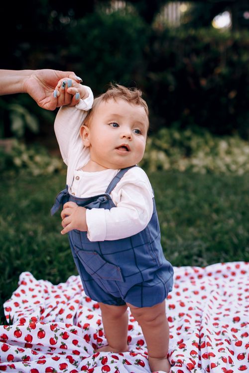 Free Cute toddler standing on a blanket outdoors, exuding joy and innocence. Stock Photo