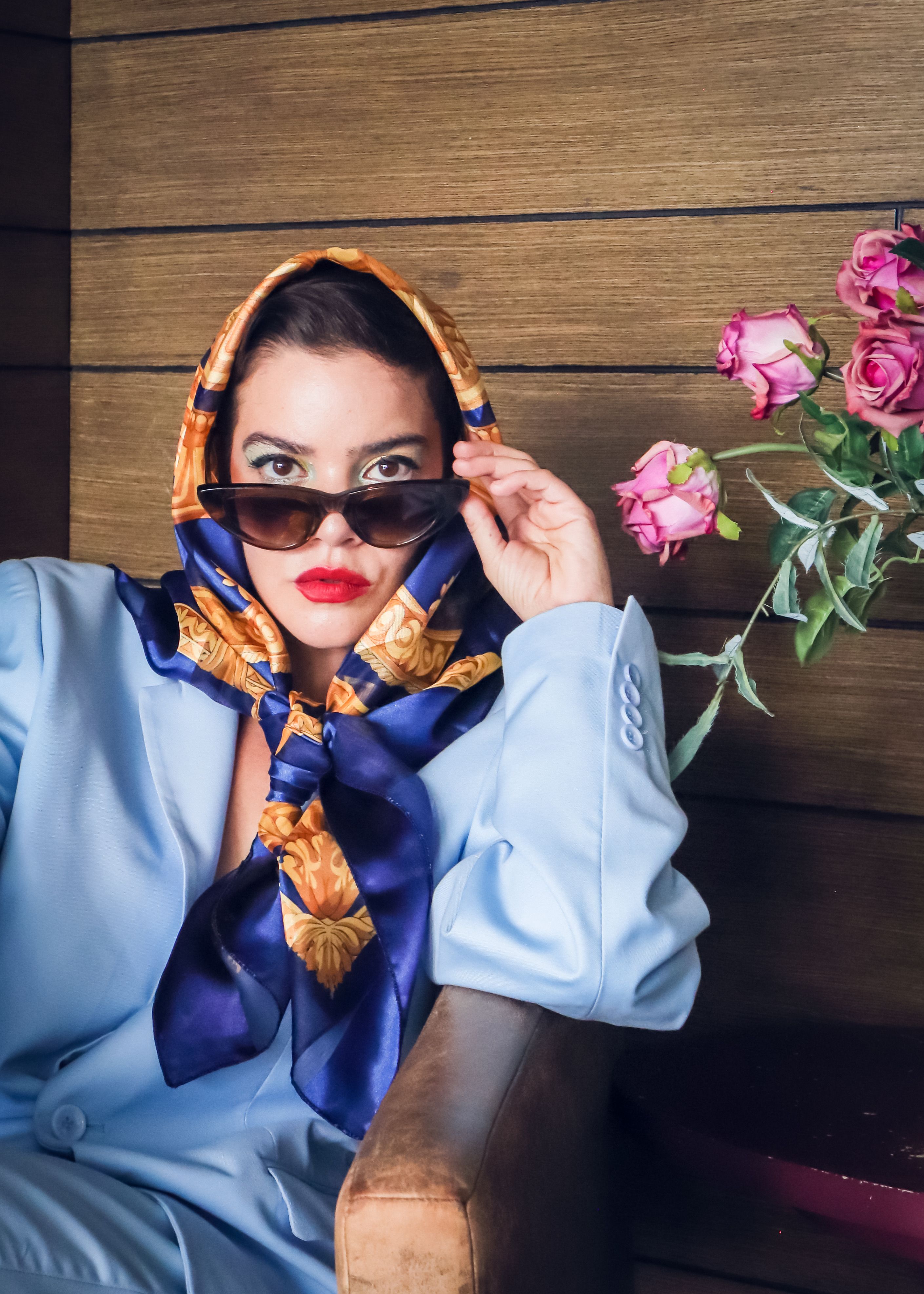 Elegant woman in sunglasses and scarf with roses, embodying fashion and sophistication.