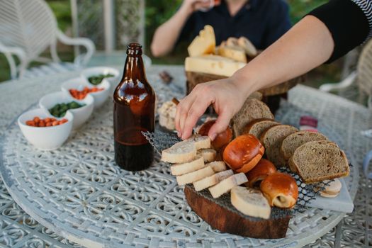 Enjoying a casual outdoor gathering with bread, cheese, and beer on a decorative table.