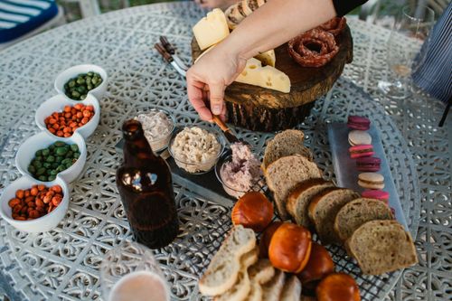 Free A table with cheese, salami, bread, dips, and snacks, ideal for a casual outdoor gathering. Stock Photo