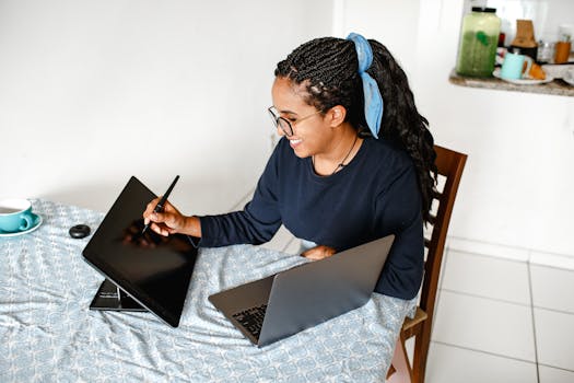 Smiling woman using digital tablet and laptop at home office, showcasing creativity and technology.