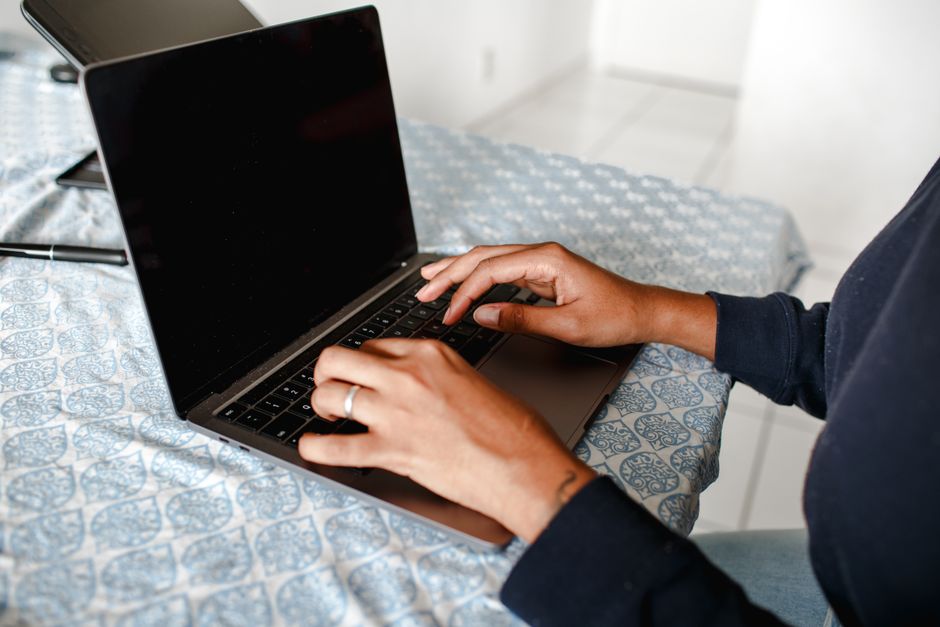 How to Remove Your Personal Data from the Internet Safely Close-up of hands typing on a laptop indoors on a patterned tablecloth.