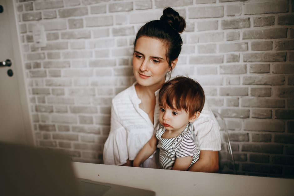 Baby Brezza Formula Pro Advanced vs Manual Bottle Prep: Safety and Convenience Compared A mother and child engage with a laptop indoors, showcasing a peaceful family moment.