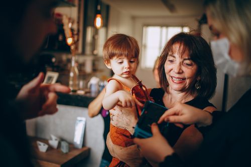 Free Heartwarming moment of a grandmother holding a child at a family gathering indoors. Stock Photo