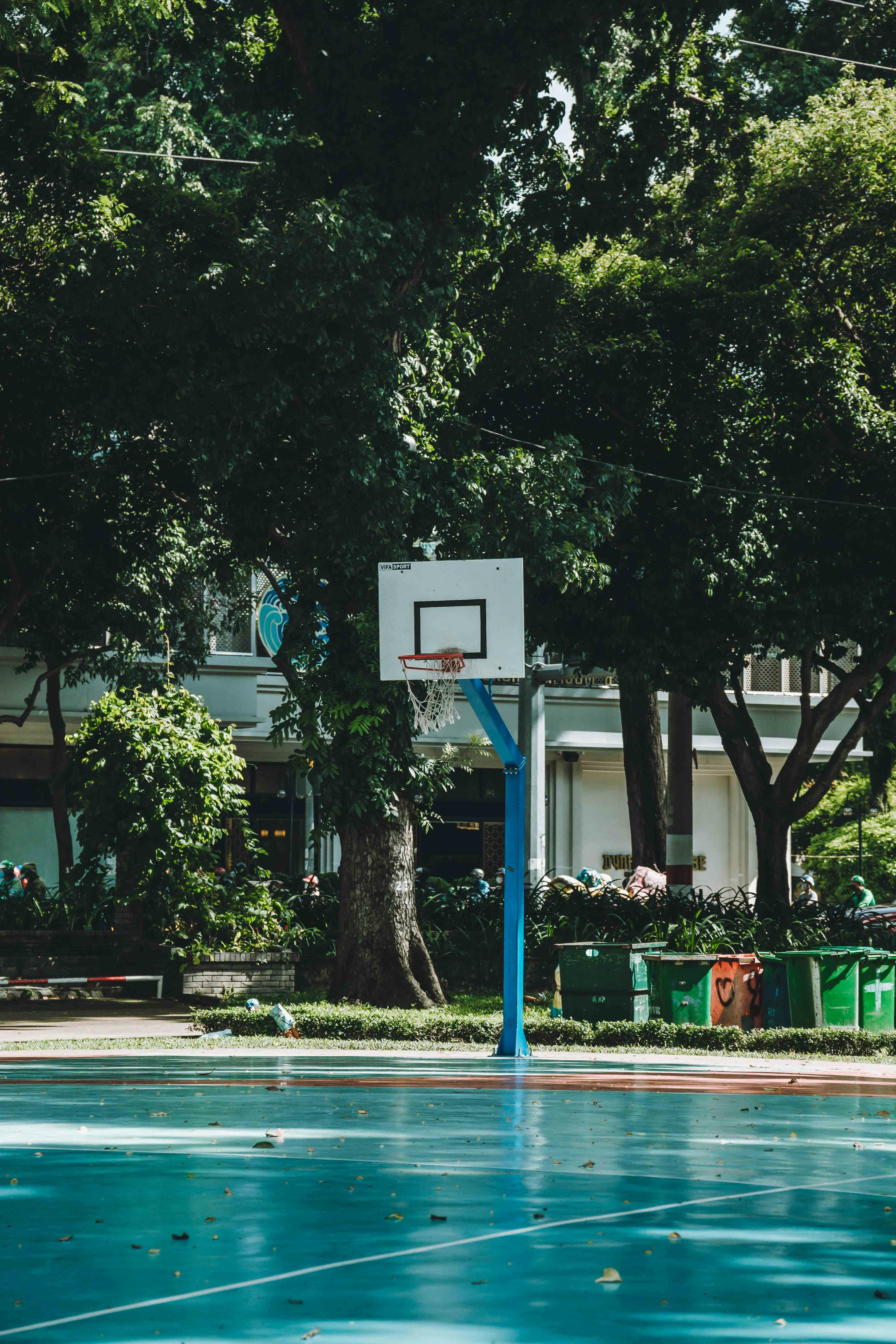 Free Bright outdoor basketball court surrounded by lush trees in Ho Chi Minh City. Stock Photo