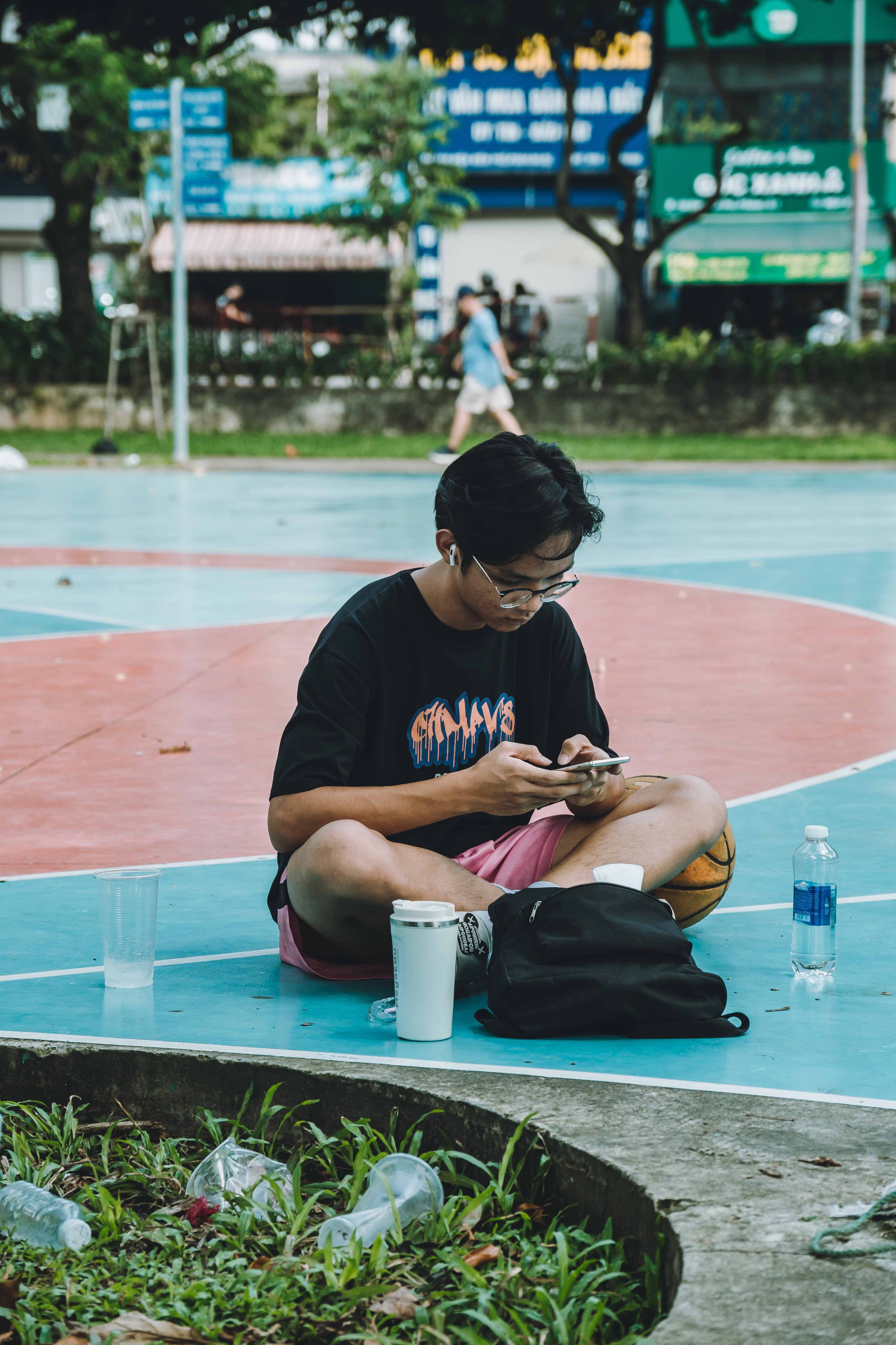 Boy Sitting with Smartphone at Park