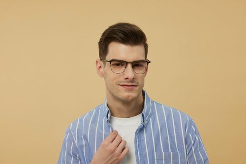 Free Portrait of a young man wearing glasses and a striped shirt, looking confidently at the camera. Stock Photo