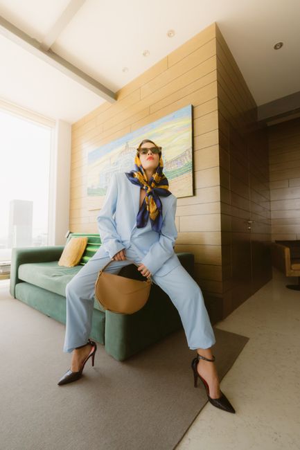 Fashionable woman in a blue suit posing confidently in a luxury Mexico City apartment.