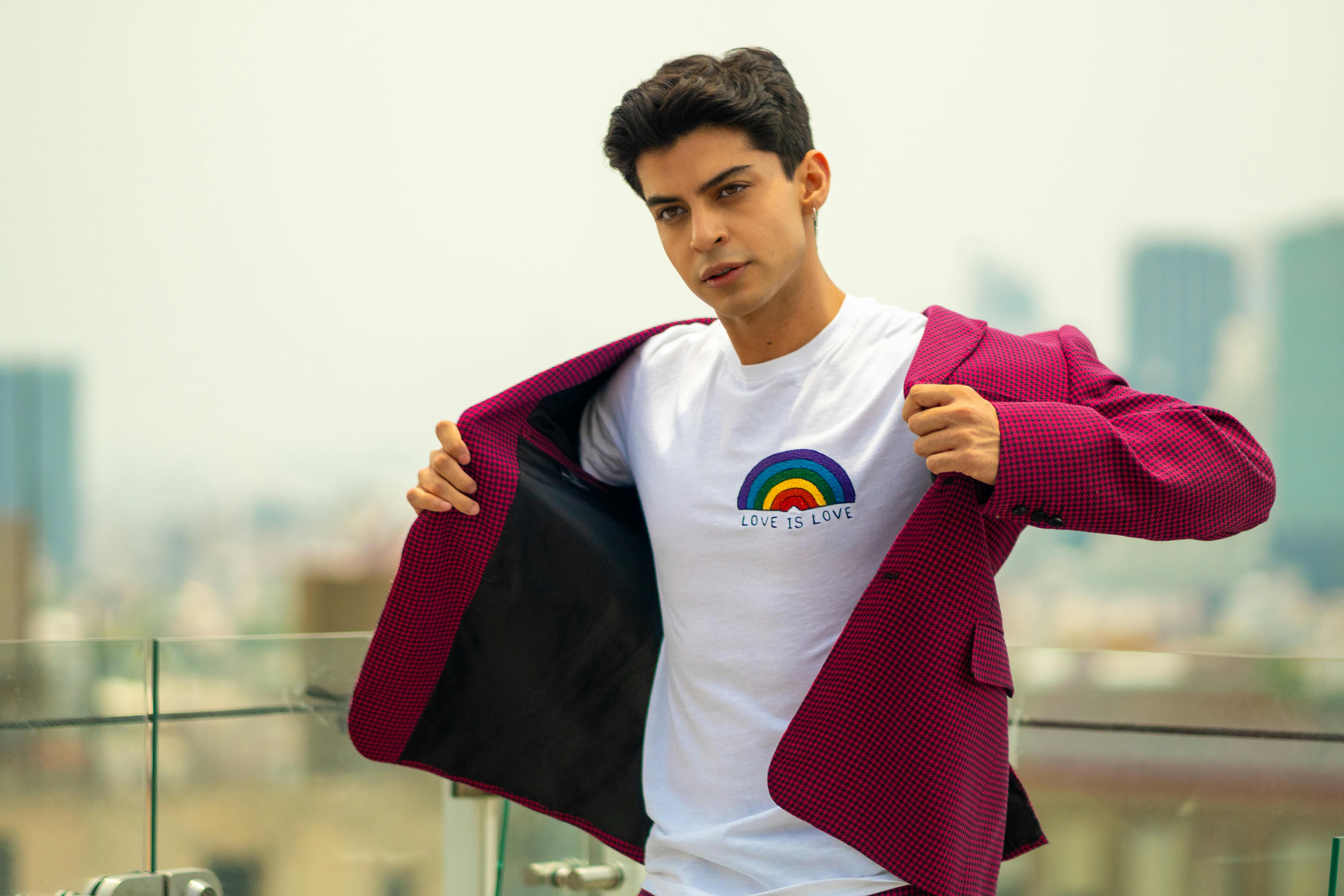 man in pink jacket and white t shirt posing on balcony