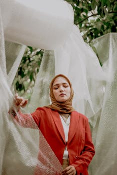 一位时尚女性，头戴头巾、身着红色西装外套，其肖像在户外被气泡纸包围