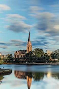 Beautiful shot of St. Bartholomew's Cathedral reflecting in the river, under a serene sky in Frankfurt.