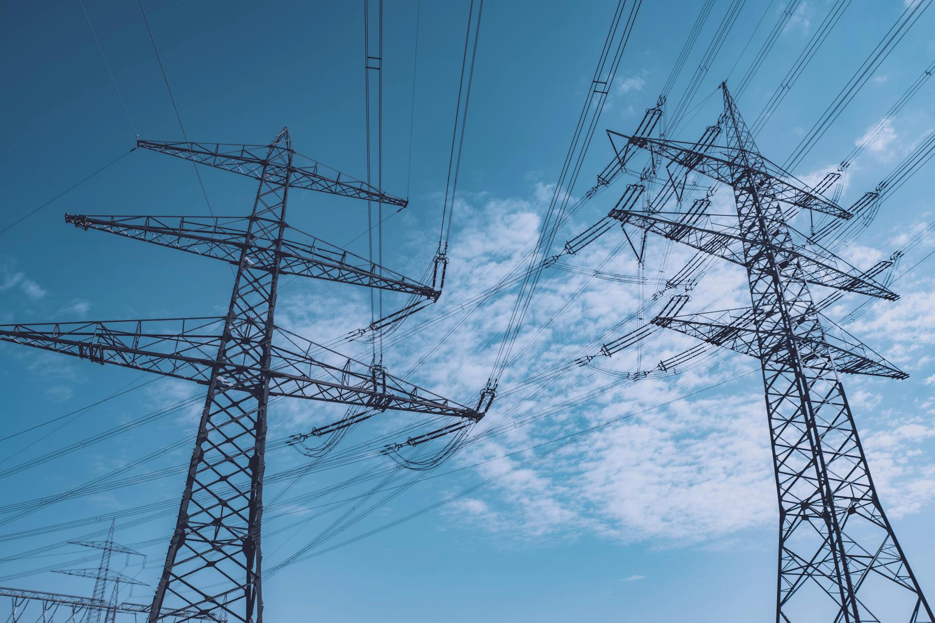 High voltage transmission towers stretch across a clear blue sky, symbolizing energy and industry.