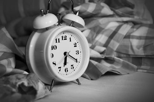 White Alarm Clock on Bed
