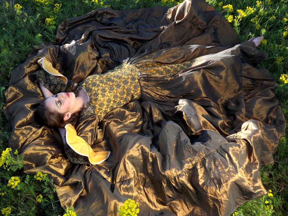 無料 緑の草の上に横たわっている黒と黄色のドレスを着ている女性 写真素材