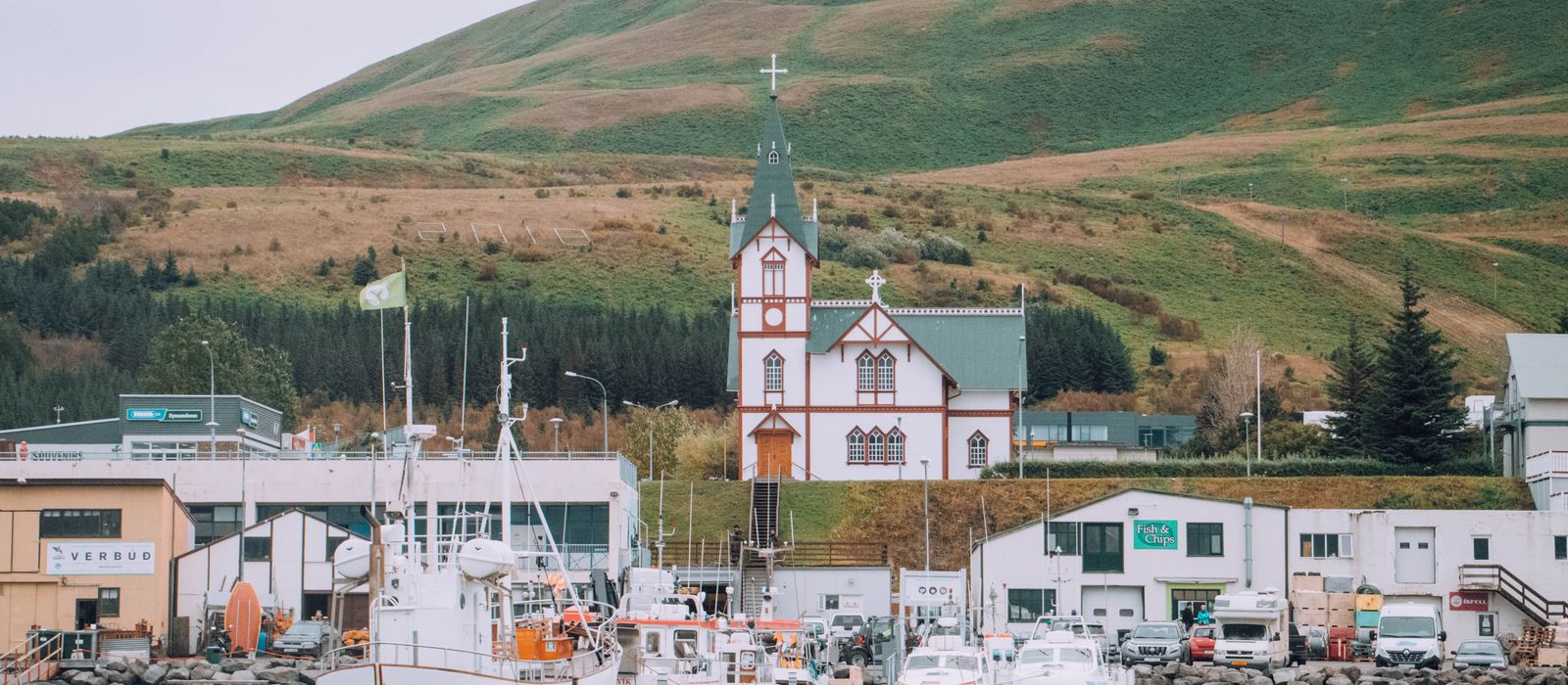 Charming harbor scene with classic church and boats in Húsavík, Iceland.