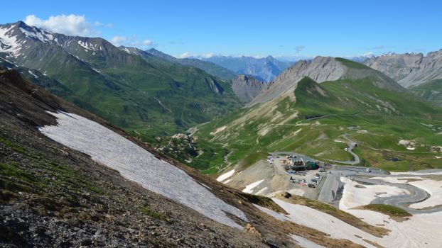 Breathtaking view of a mountainous landscape featuring patches of snow and a winding road.