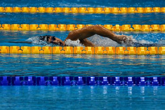 A swimmer in mid-stroke at an outdoor pool, showcasing dynamic aquatic sports action.