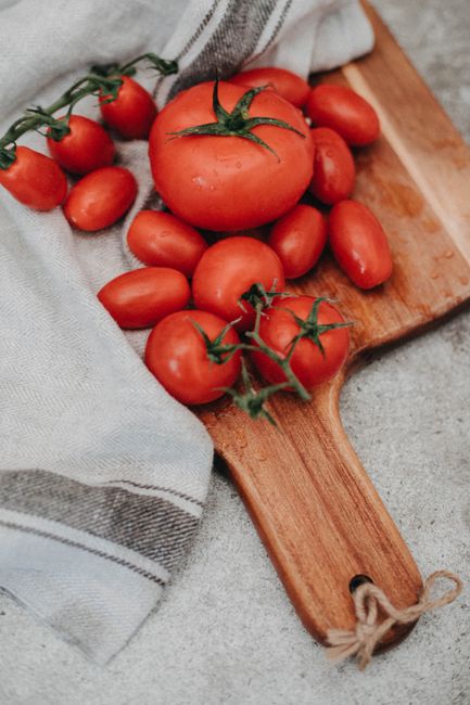 A collection of ripe tomatoes on a wooden chopping board, perfect for culinary presentations.