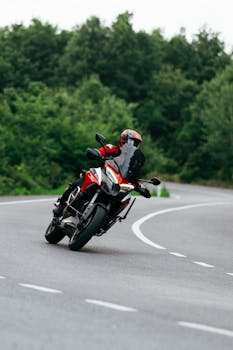 Motorcyclist in helmet rides a powerful bike on outdoor curvy road.