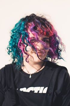 一位女士留着鲜艳的卷发，在户外微笑着