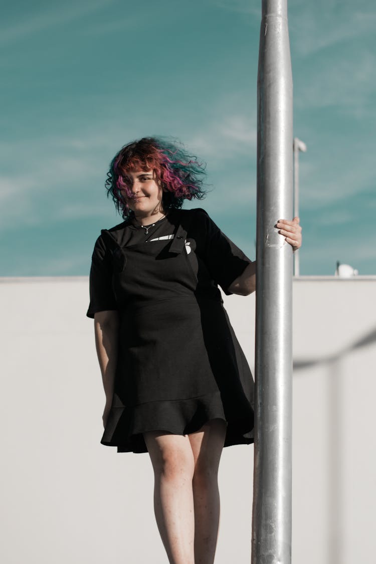 Woman In Black Dress Holding On Pole