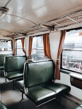 Explore a classic train carriage interior featuring retro green leather seats and vintage decor.