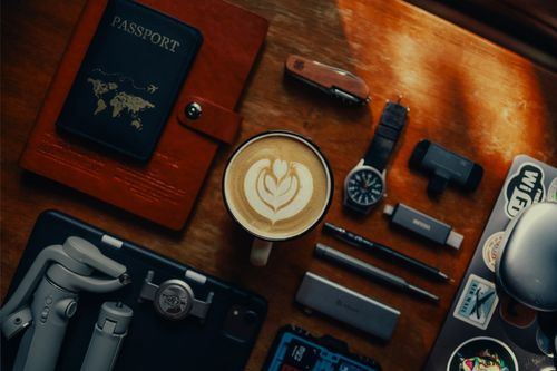 Free Flat lay of travel essentials with coffee, gadgets, and a passport on a wooden table. Stock Photo