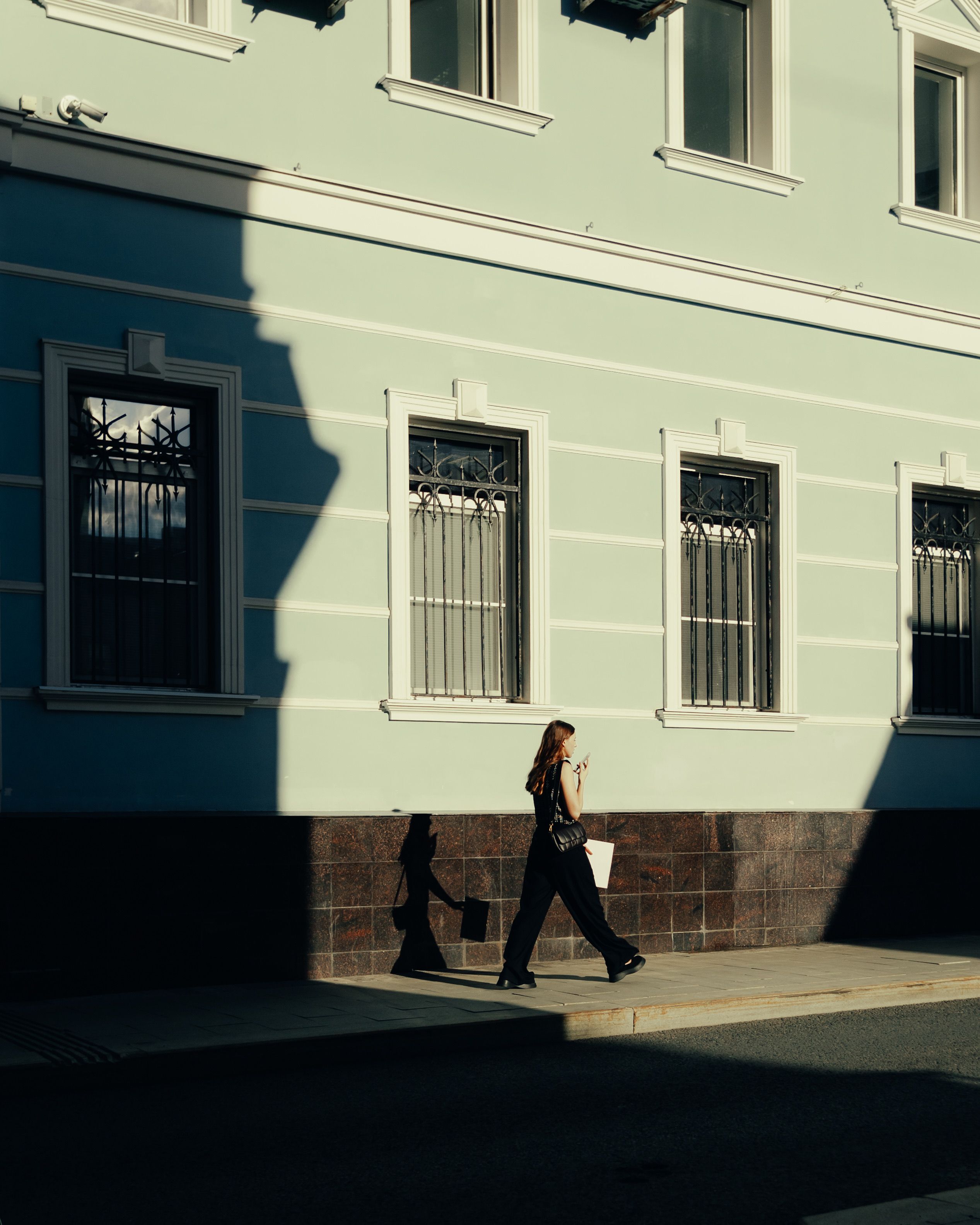A woman walking down the street in front of a building · Free Stock Photo