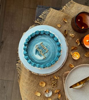 A beautifully decorated blue birthday cake with candles, creating a warm and cozy setting.