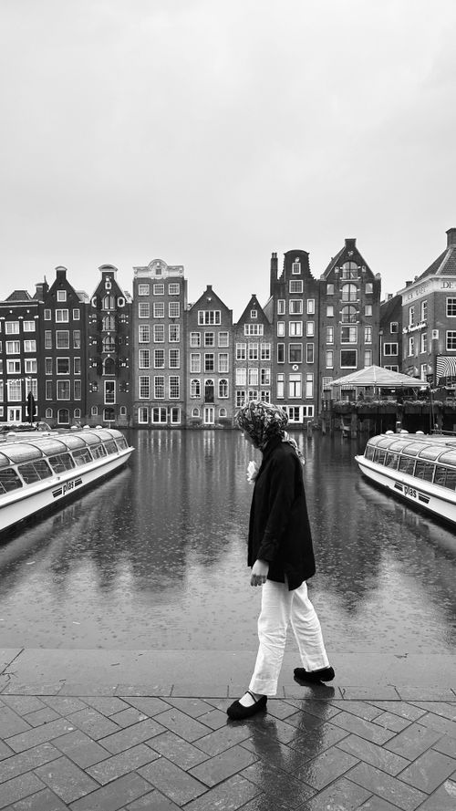 Free Black and white photo of a canal with historic buildings and a person walking. Stock Photo