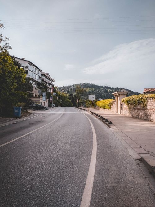 Free A quiet urban street with adjacent buildings leading to a scenic mountain view under a clear sky. Stock Photo