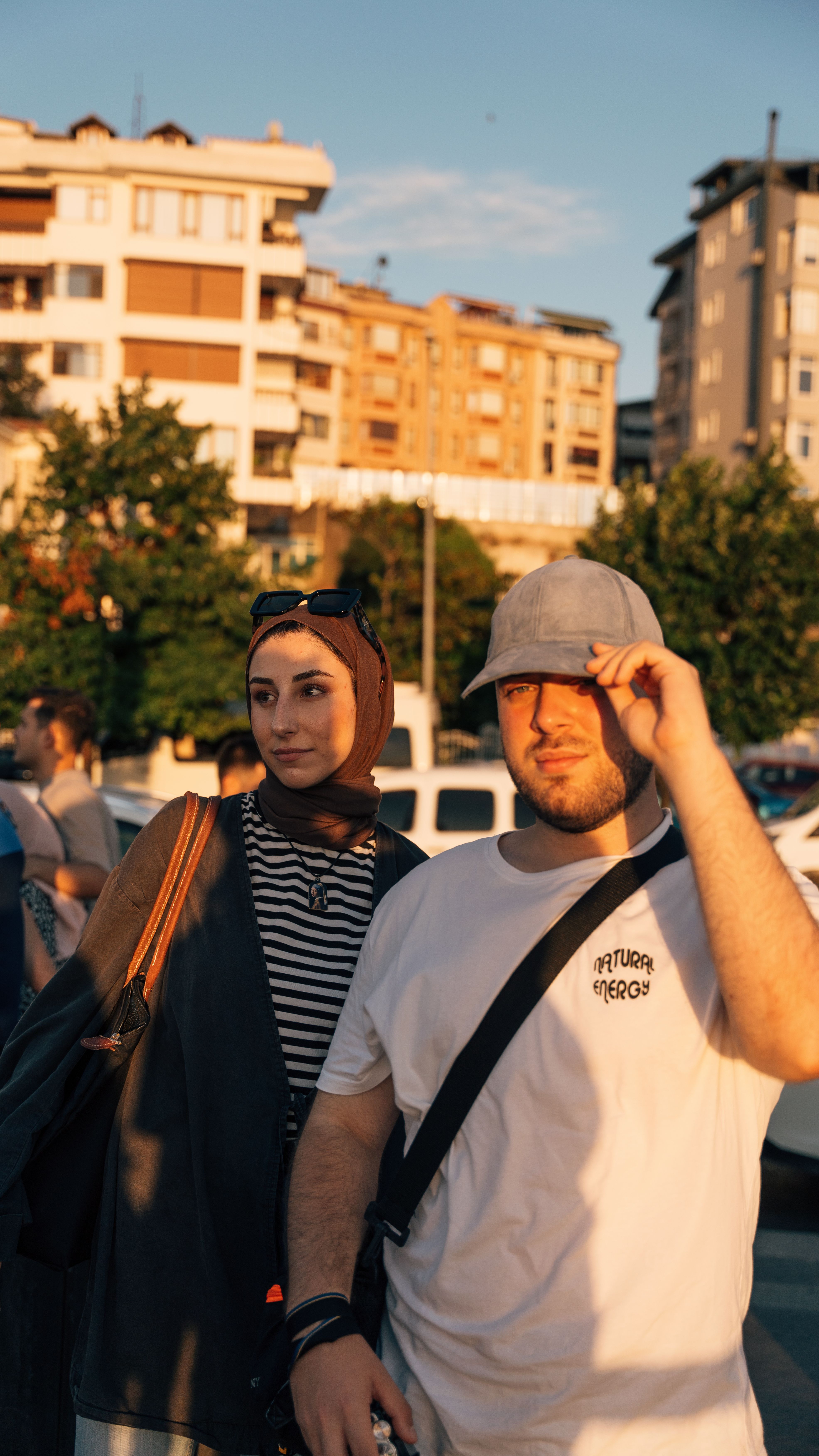 Two young adults enjoying a sunny day in a vibrant urban area, surrounded by modern buildings.