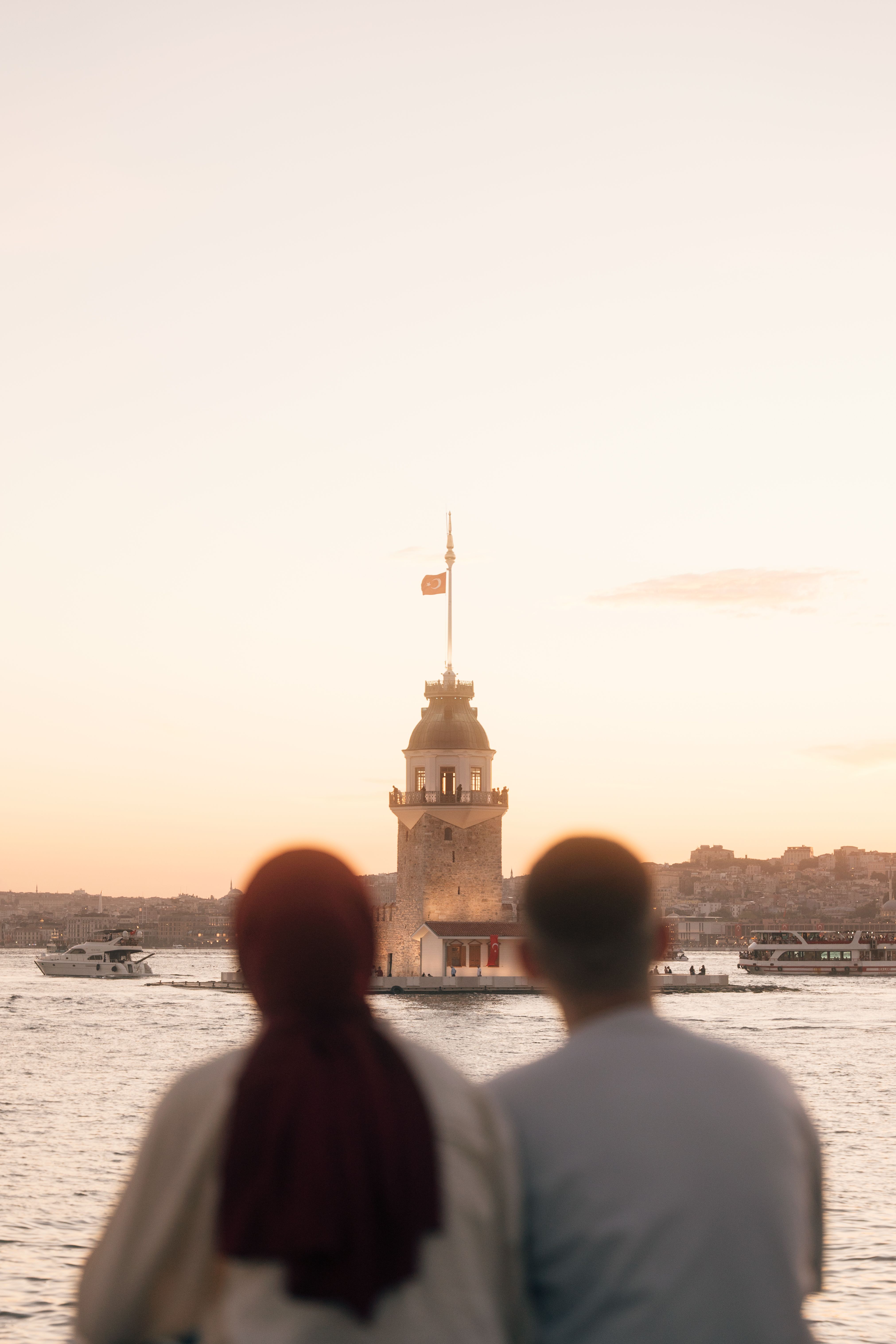 Two people sitting on a bench looking at the water · Free Stock Photo