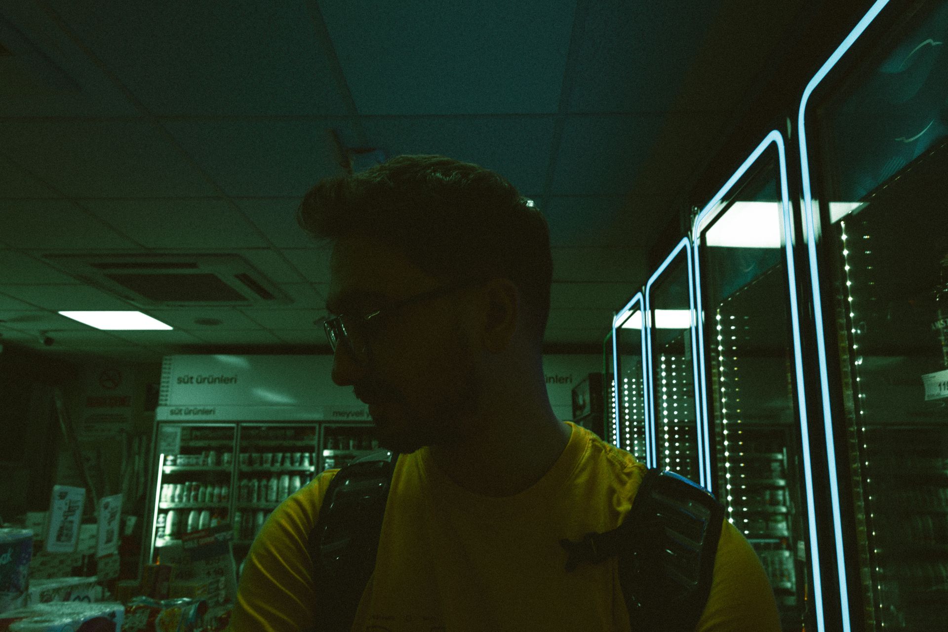 Silhouette of a man in a supermarket illuminated by ambient neon light.