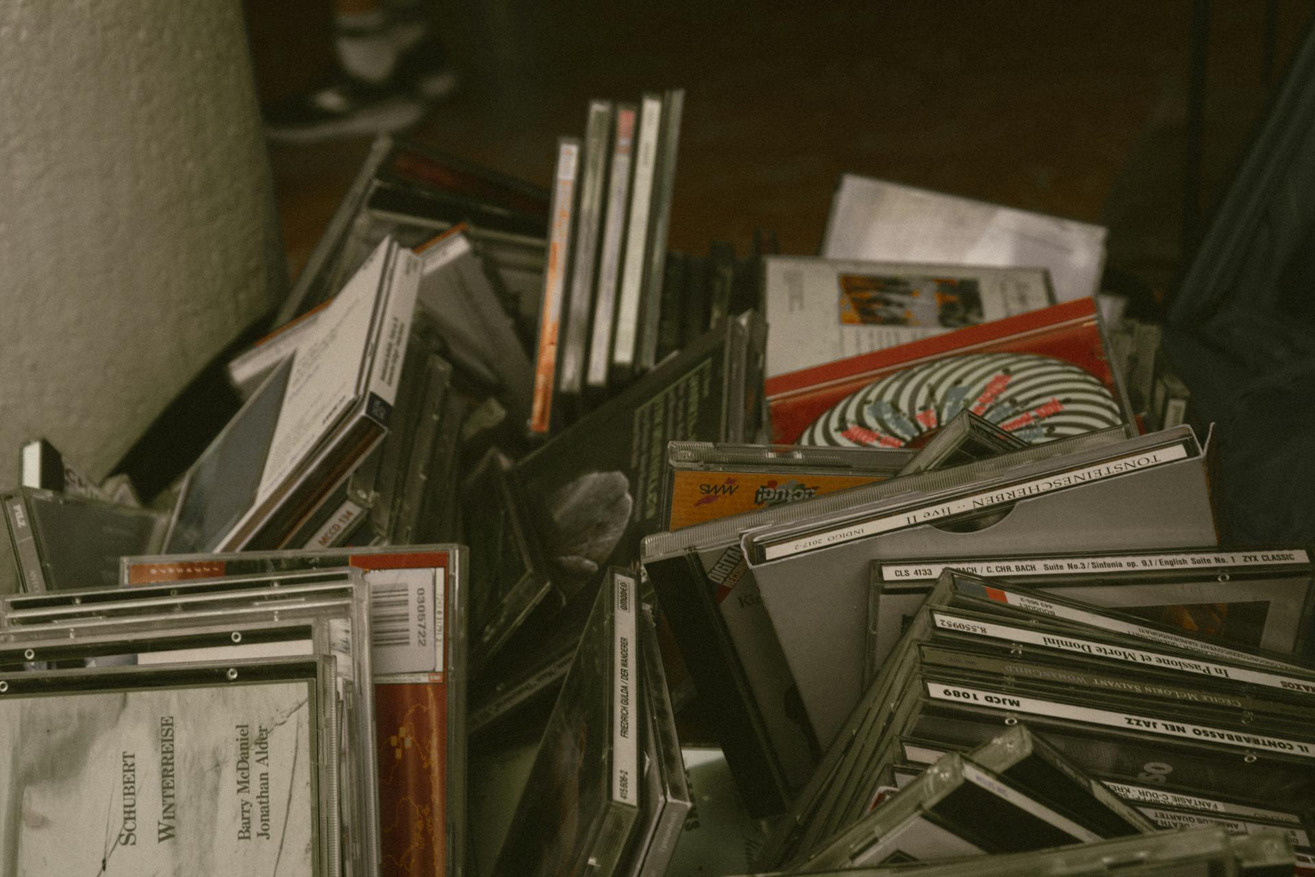 A cluttered pile of CD cases showcasing a nostalgic collection in a dimly lit room.