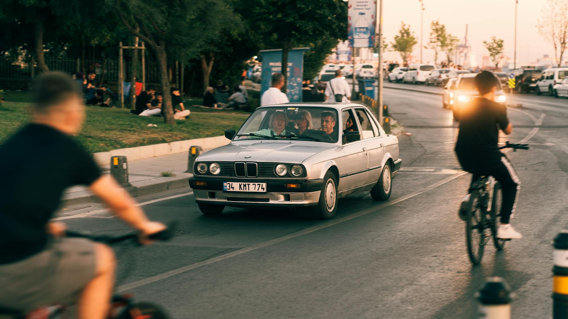 A dynamic city street scene with cyclists and a car amidst evening traffic.