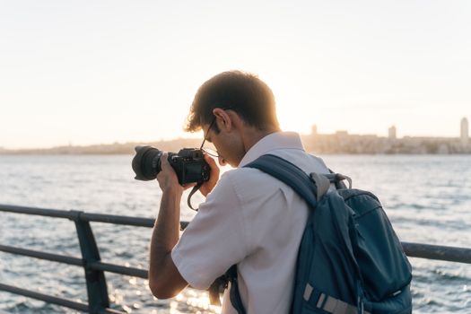 A male photographer captures stunning shots by the waterfront during sunset.
