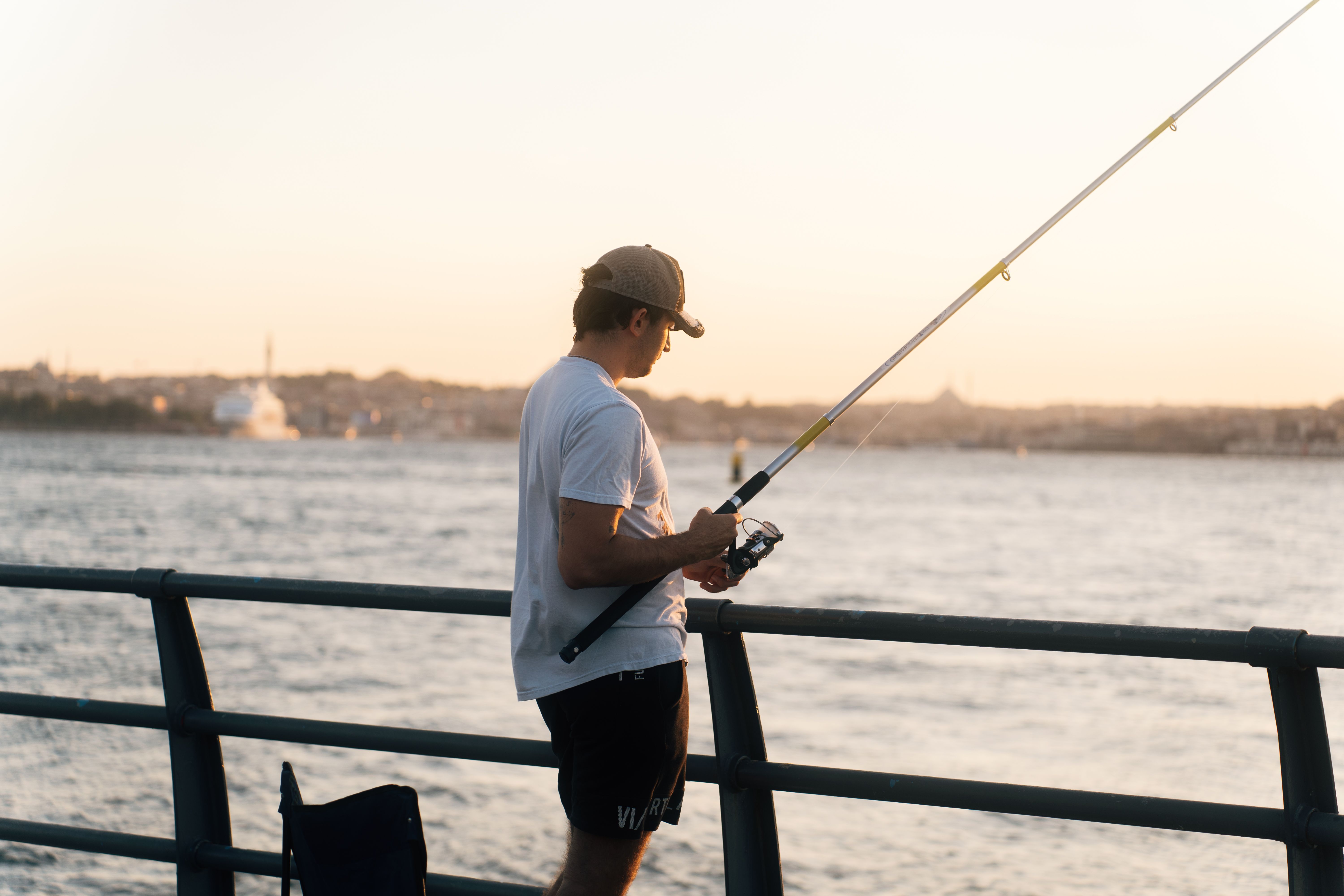 堤防でフィッシュグリップを使い魚を持つアングラー