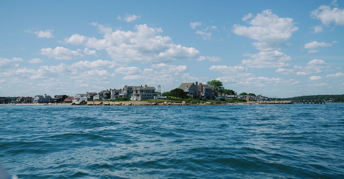 Beautiful coastal landscape featuring houses on a seashore under a blue sky.