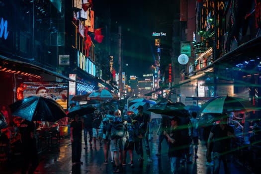 Captivating street scene of nightlife in Hồ Chí Minh City with neon lights and umbrellas in the rain.