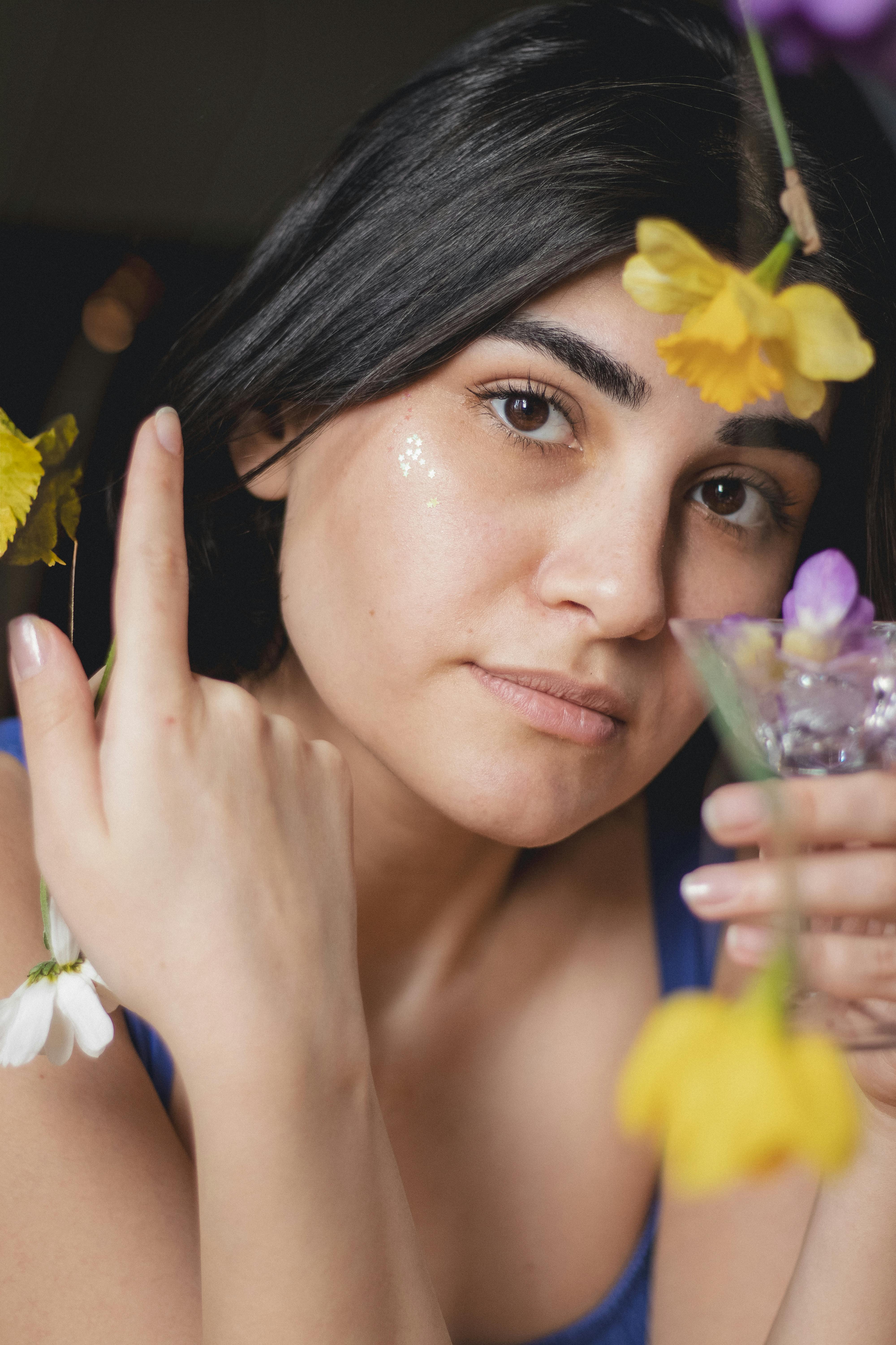 A woman holding a glass of flowers in her hand 