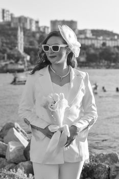 Elegant bride in a modern suit with a veil and bouquet, set against an urban backdrop.