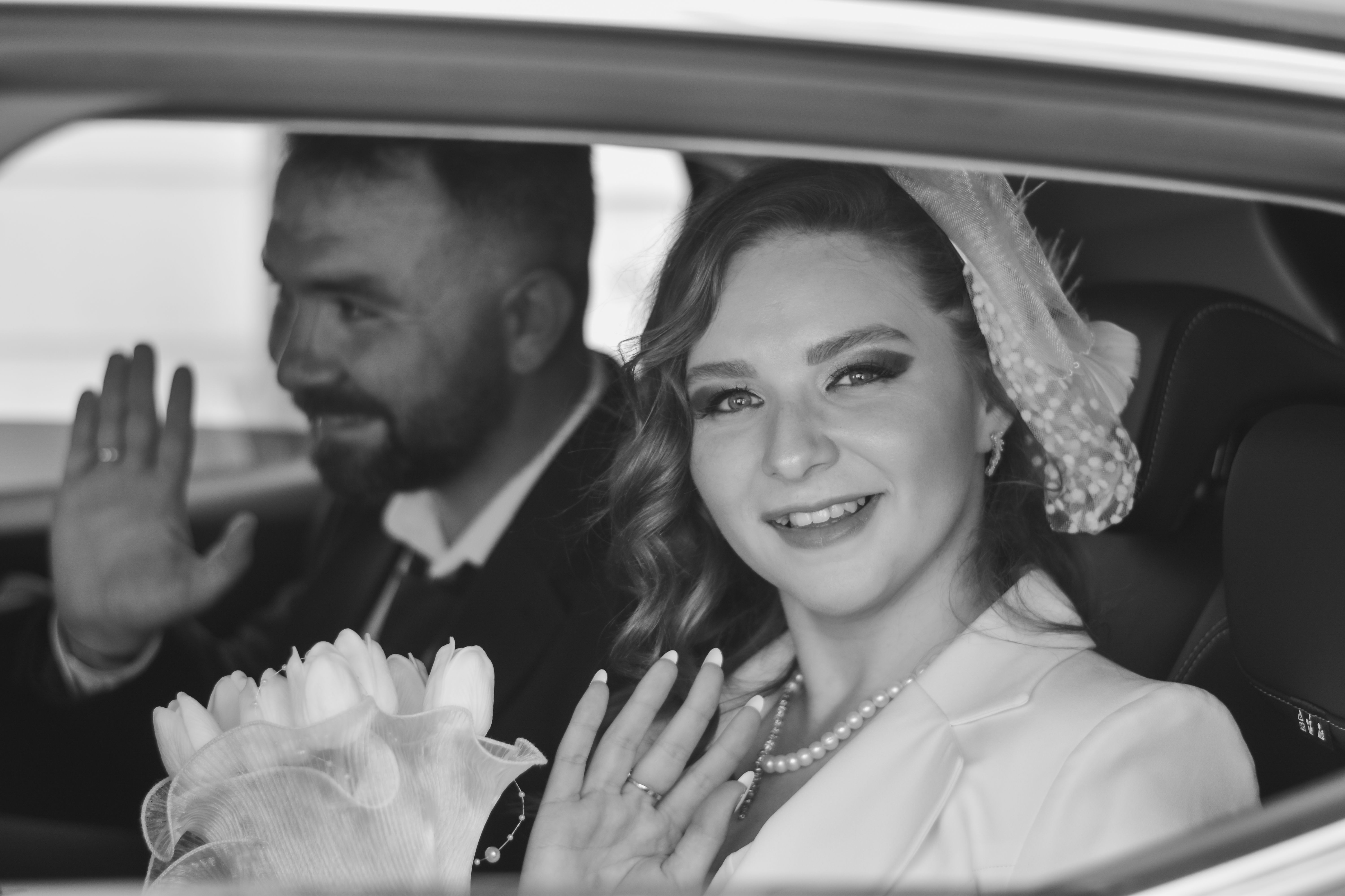 A bride and groom in a car waving at the camera · Free Stock Photo