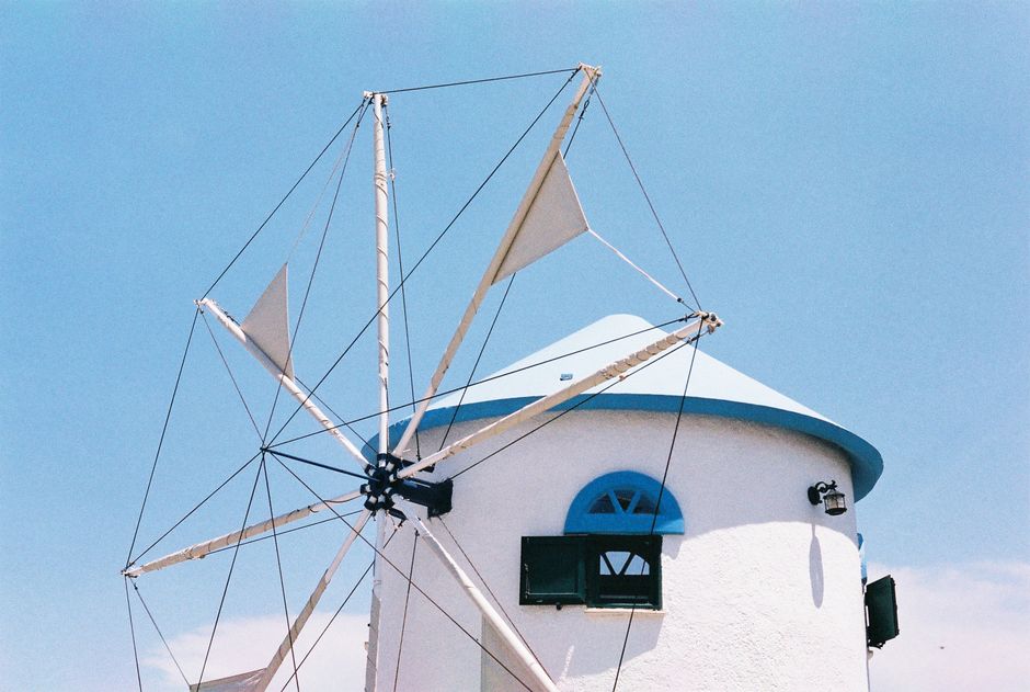 A white windmill with blue accents set against a bright blue sky, exuding a classic and airy feel.
