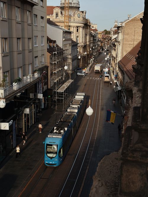 Free A blue tram travels down a bustling street in a historic European city, showcasing urban transportation. Stock Photo